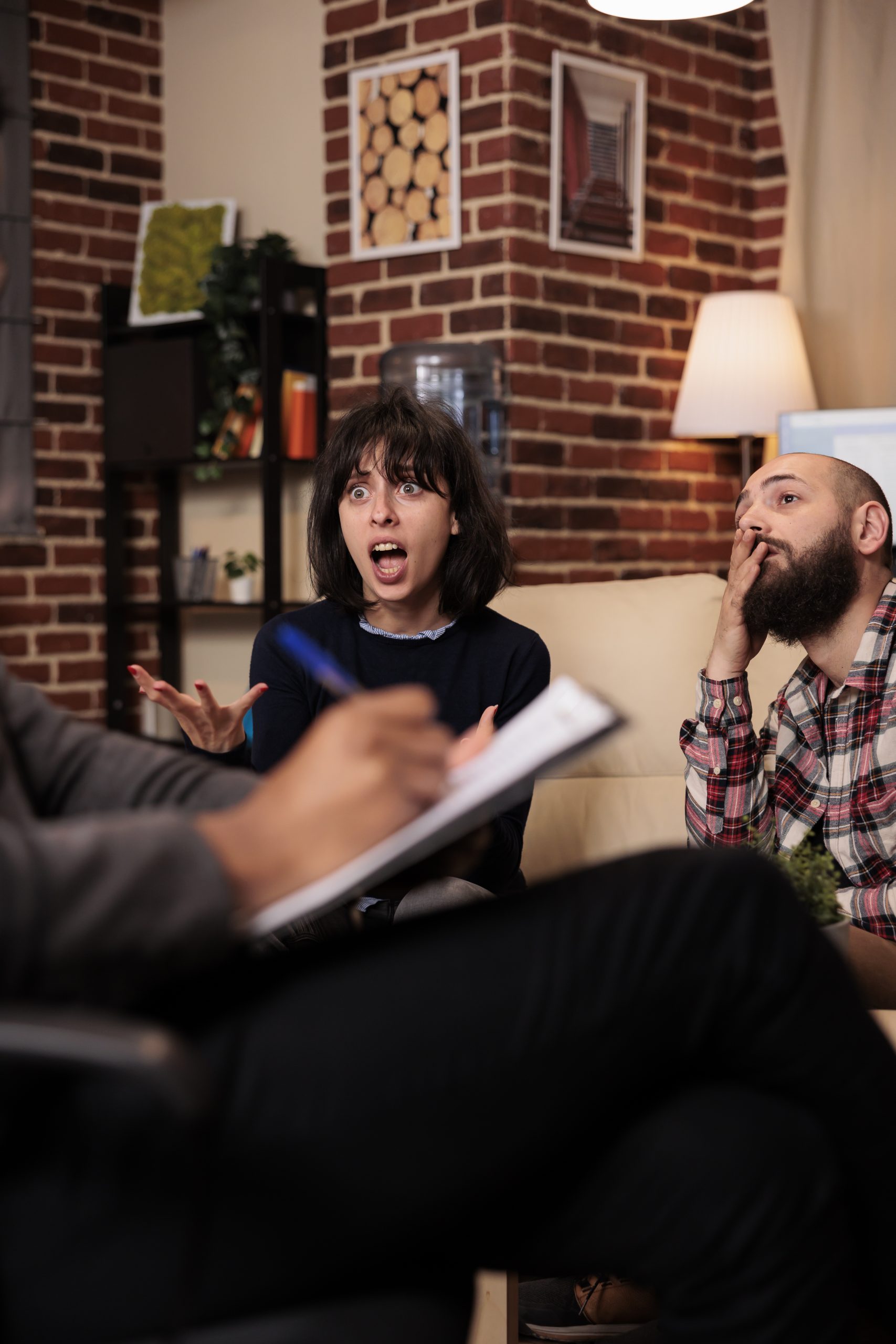 Male psychologist taking notes on paper at couple therapy