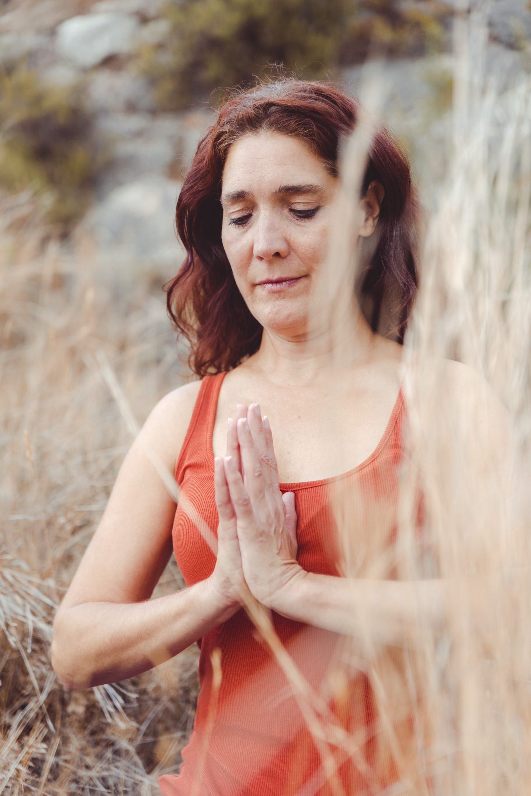 portrait of woman with posture of gratitude and eyes closed in field
